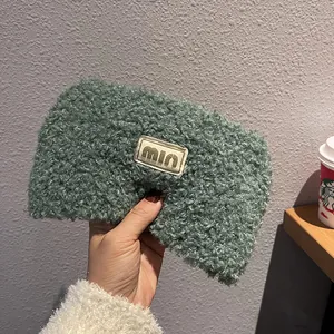 Close-up of green teddy fleece headband featuring a woven label with gold text