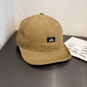 Detail of khaki canvas short brim cap featuring embroidered logo patch and peak design