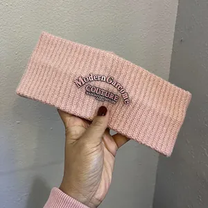 Close-up of pink ribbed knit headband featuring a modern couture embroidered patch