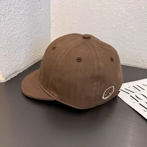 Close-up of the smiley face embroidery on the brown cotton soft top baseball cap