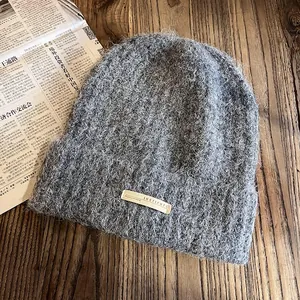 Détail du bonnet en maille gris pelucheux avec texture mohair et étiquette tissée