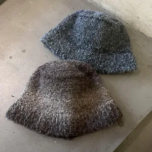 Thick mixed color knit bucket hats in dark grey and coffee brown on grey concrete surface