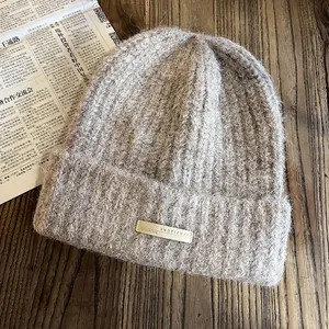 Gros plan du bonnet en maille épaisse kaki avec texture mohair douce et écusson brodé