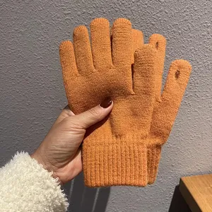 Detail der orangefarbenen Strickhandschuhe mit Touchscreen-Fingern und Rippbündchen