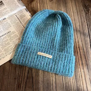 Gros plan du bonnet en tricot côtelé bleu avec étiquette sur une table en bois