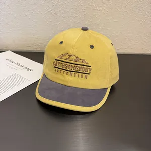 Detail of yellow and grey patchwork baseball cap with embroidered mountain graphics