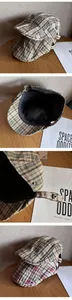 Detail of vintage plaid flat cap featuring bronze metal buckle and breathable mesh lining