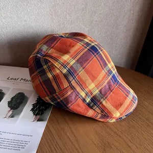 Détail d'une casquette plate à carreaux colorés posée sur un bureau en bois avec un livre