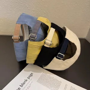 Stack of colorful cotton baseball caps in blue, yellow, black, and beige with metal buckles