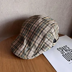 Detail view of khaki green plaid flat cap texture with adjustable metal buckle on wood