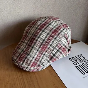 Close-up of a classic red and black plaid newsboy cap on a rustic wooden background