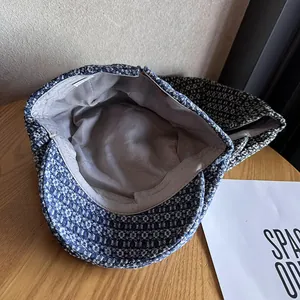 Blue and white jacquard flat cap in vintage denim style on a minimalist wooden surface