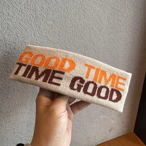 Dettaglio della fascia sportiva in maglia beige con scritte GOOD TIME arancioni