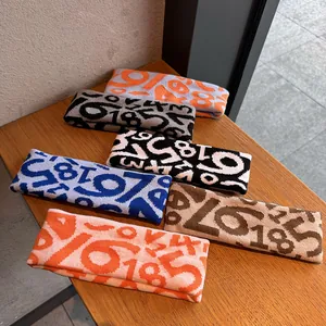 Detailed view of six colorful knitted sports headbands with numeral jacquard on wood