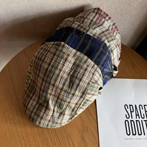 Stack of vintage plaid flat caps in khaki green and navy blue with a classic textured finish