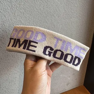 Dettaglio della fascia sportiva beige in maglia con testo GOOD TIME viola e nero