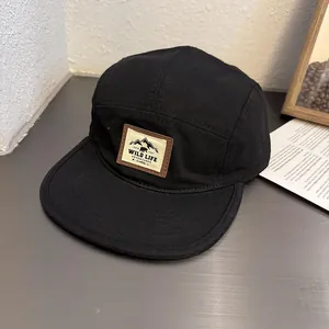 Detail of black five-panel camper hat with mountain and bear outdoor adventure patch