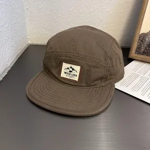Macro detail of dark brown 5-panel camper hat with wild life embroidered patch