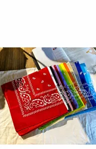 Close-up of stacked colorful polyester paisley bandanas in red, purple, green, and blue