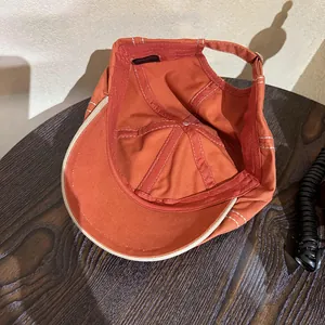 Orange vintage cotton newsboy cap with white stitching and adjustable metal buckle