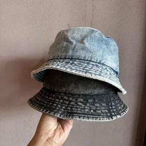 Detail of washed denim bucket hats in light blue and charcoal with frayed edge design