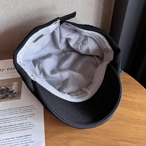 Retro black cotton newsboy cap featuring a grey lining and adjustable metal buckle back