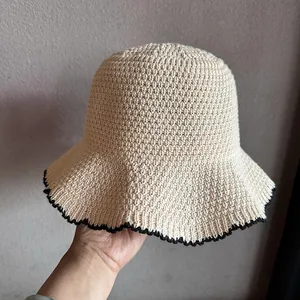 Detail van beige gebreide vissershoed met zwart contrastrandje en golvende randstructuur
