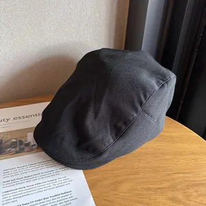 Detailed texture of black vintage flat cap on a wooden table with fashion magazine