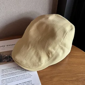 Detailed close-up of a beige knitted flat cap on a wooden surface for vintage styling
