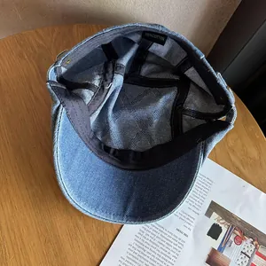 Interior detail of a 100% cotton denim flat cap showing metal eyelet and washing label