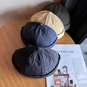 Bonnets Docker vintage en noir bleu beige et vert présentés sur une table en bois