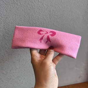 Nahaufnahme eines rosa Strick-Stirnbands mit dunkelrosa Schleifenmuster aus weichem Stoff