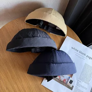 Gros plan de trois bonnets miki en kaki, noir et bleu marine sur un bureau en bois