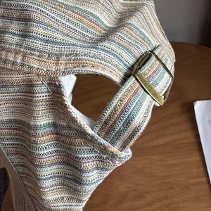 Dettaglio della fibbia in ottone e trama intrecciata a righe di un cappello newsboy