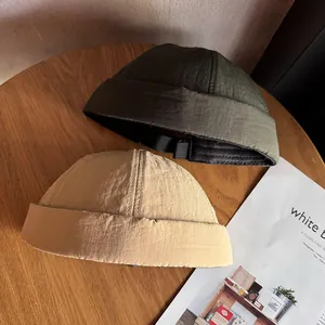 Bonnets docker vert armée et kaki avec sangles réglables sur une table en bois