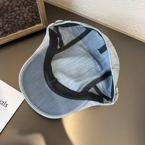 Inside view of light blue denim flat cap with black sweatband and adjustable metal buckle