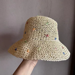 Vue détaillée d'un chapeau de paille tressé avec des broderies colorées sur texture beige