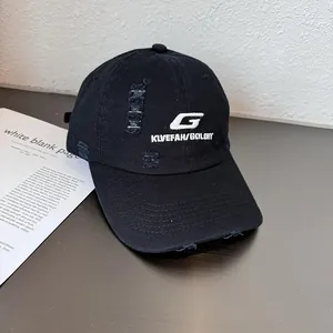 Close-up of distressed black baseball cap with white letter embroidery and ripped details