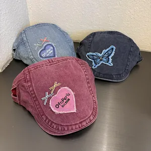 Detailed view of washed denim berets with heart embroidery and vintage frayed patches