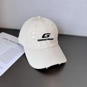Detailed view of cream distressed baseball cap with black embroidered letters G and KLVEFAH