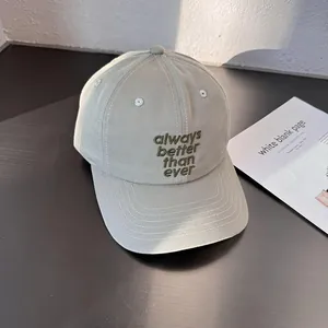 Detail of embroidered 'always better than ever' quote on light gray cotton baseball cap