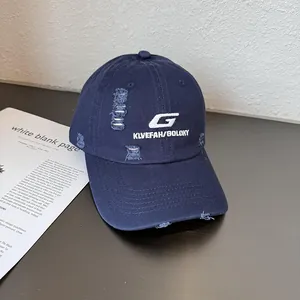 Detailed view of white letter G embroidery and distressed holes on navy blue baseball cap