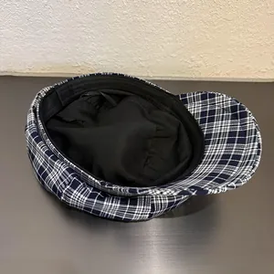 Close-up of blue plaid baker boy hat showing black fabric lining and sweatband detail