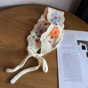 Detail of crochet floral headband with blue and orange flowers on white knit strap