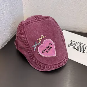 Detail of vintage washed wine red beret featuring pink heart embroidery and ribbon accents