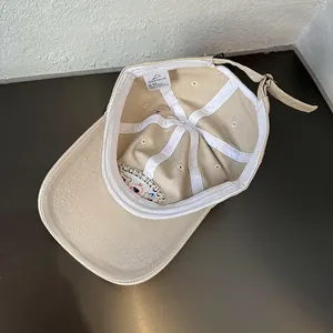 Interne details van de beige katoenen pet met witte zweetband en metalen verstelbare gesp