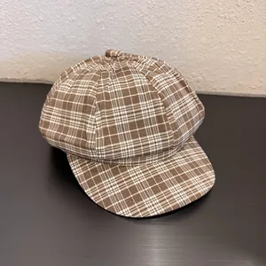 Detailed close-up of brown plaid newsboy cap with classic woven texture and octagonal top