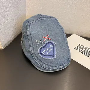 Macro detail of vintage denim beret with heart patch and Paris embroidery texture