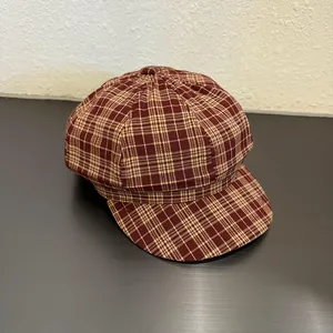 Detail of red-brown plaid octagonal baker boy hat with retro checkered fabric texture