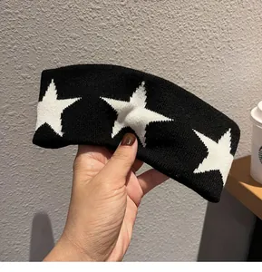 Close-up of black knitted headband featuring white star patterns and thick texture